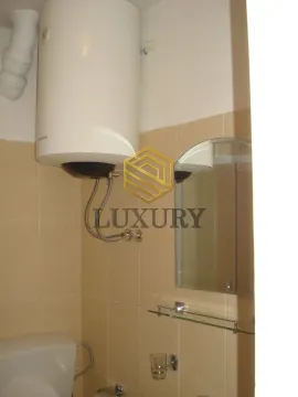 A view of the bathroom with a water heater and a mirror. - image 7