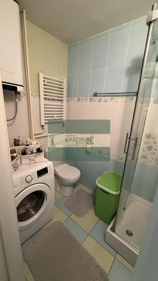 Kupatilo opremljeno tuš kabinom, WC šoljom i mašinom za veš.
