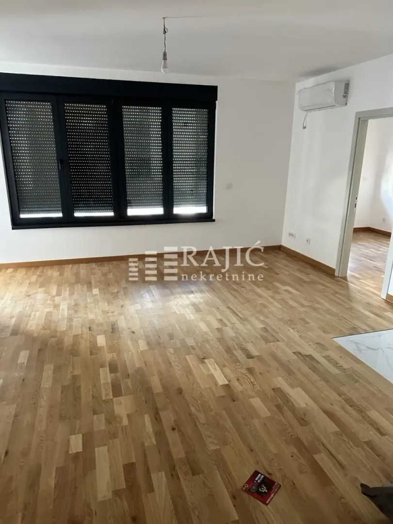 Empty room with parquet flooring and windows with closed shutters.