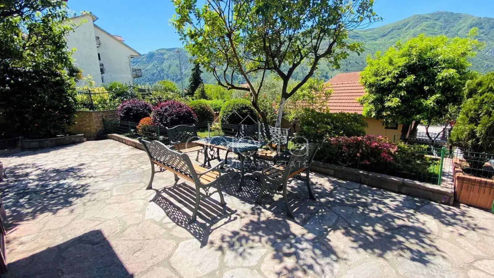 Paved courtyard with seating furniture and greenery.