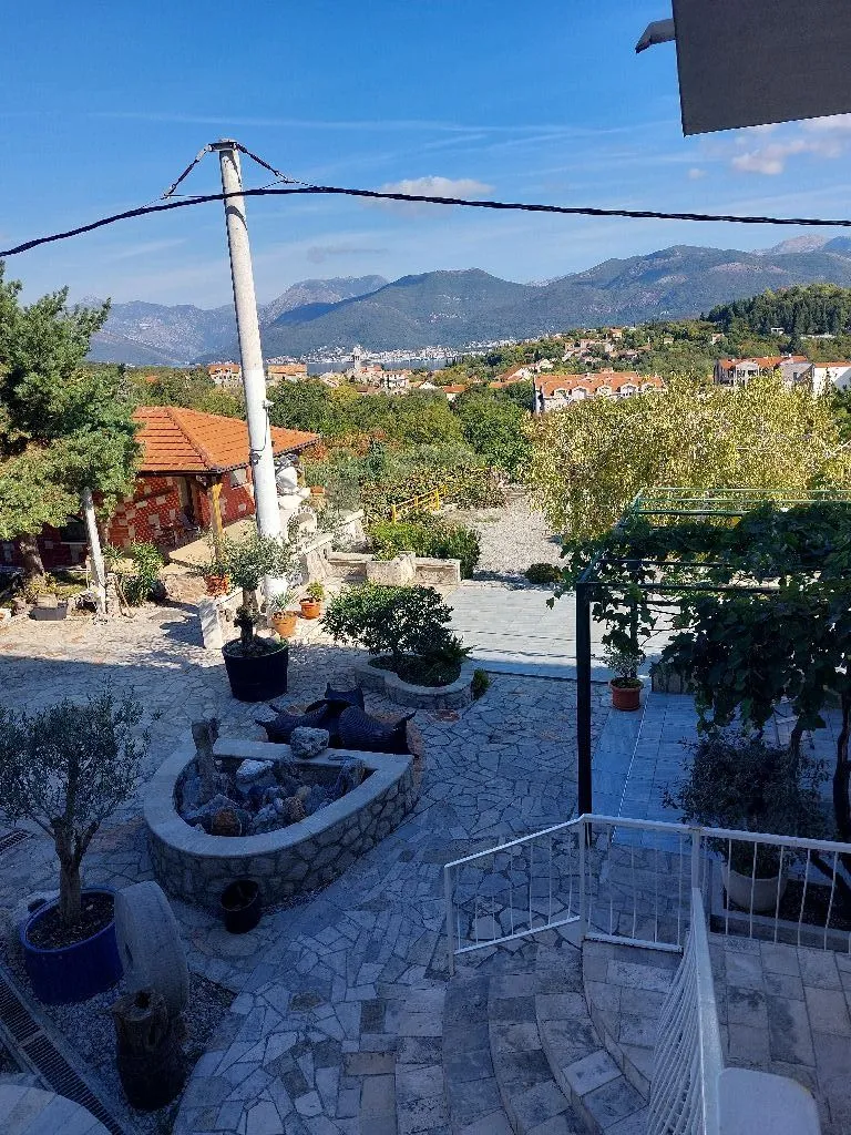 Pogled sa terase na uređeno dvorište i okolne planine.