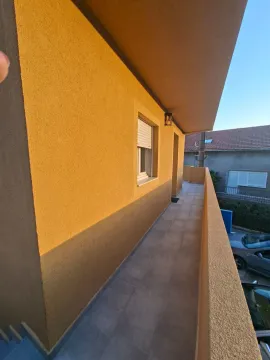 Long exterior balcony area with tiled flooring and a yellow facade wall. - image 5