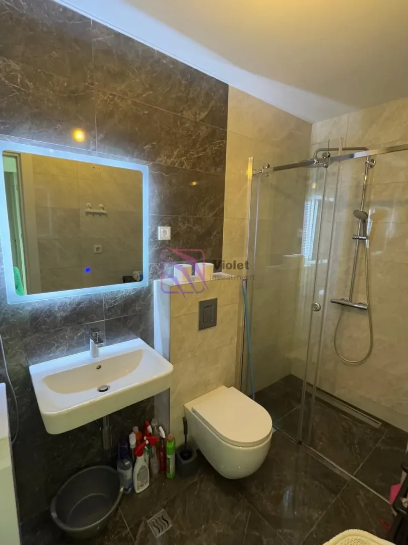 Modern bathroom with a walk-in shower, washbasin, and wall-hung toilet.