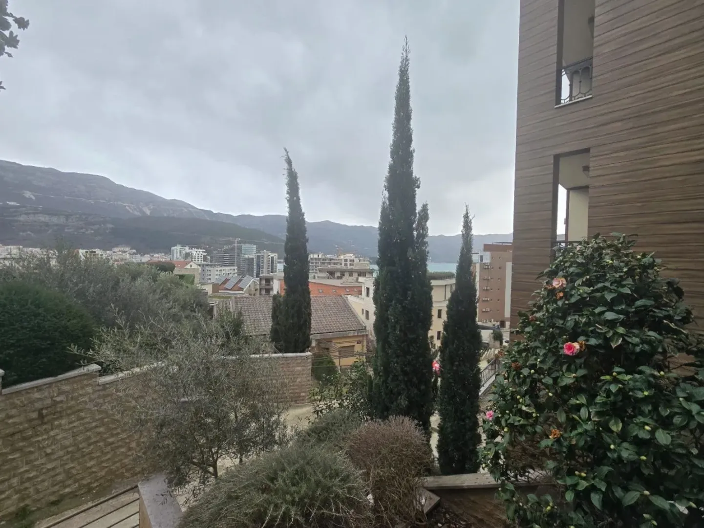 The view features the building's courtyard with cypress trees and the surrounding urban settlement in the background.