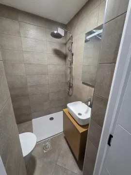 Kupatilo opremljeno tuš kabinom, umivaonikom i toaletom sa keramičkim pločicama u neutralnim tonovima. - image 9