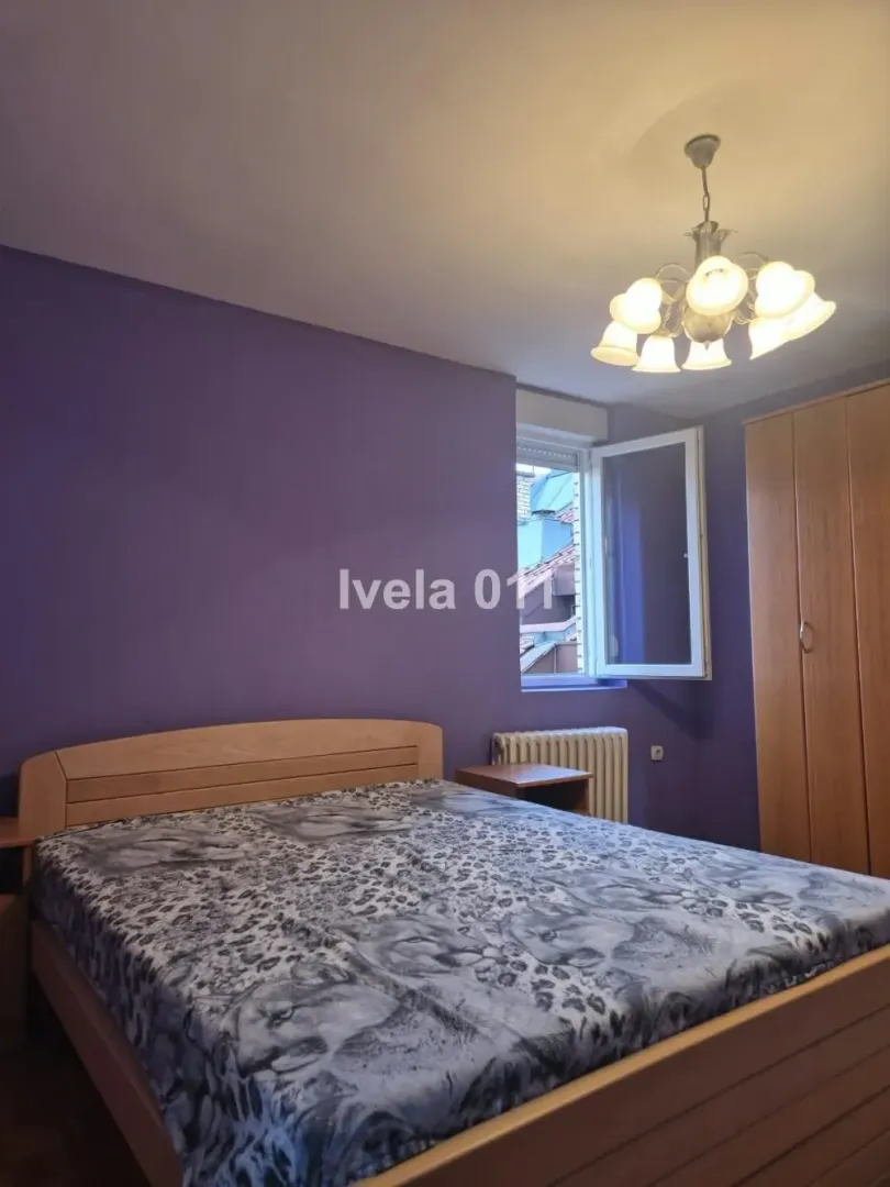 Furnished bedroom with a double bed and purple walls.