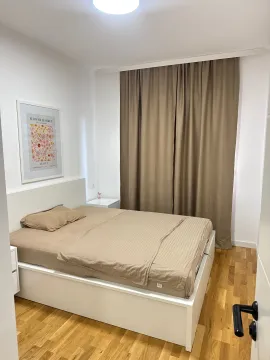 Namještena spavaća soba sa bračnim krevetom, bijelim zidovima i smeđim zavjesama. - image 5