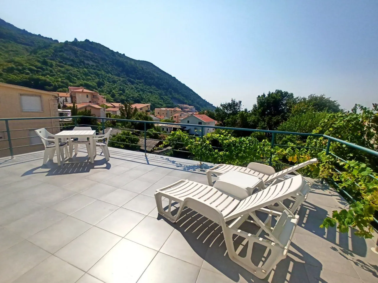 Spacious terrace with patio furniture and sun loungers with a hill view.