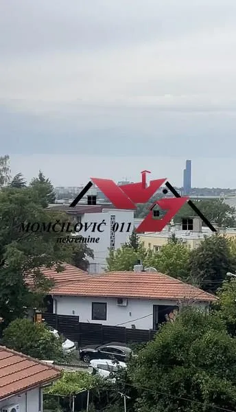 Pogled sa prozora na okolne kuće i gradski pejzaž.