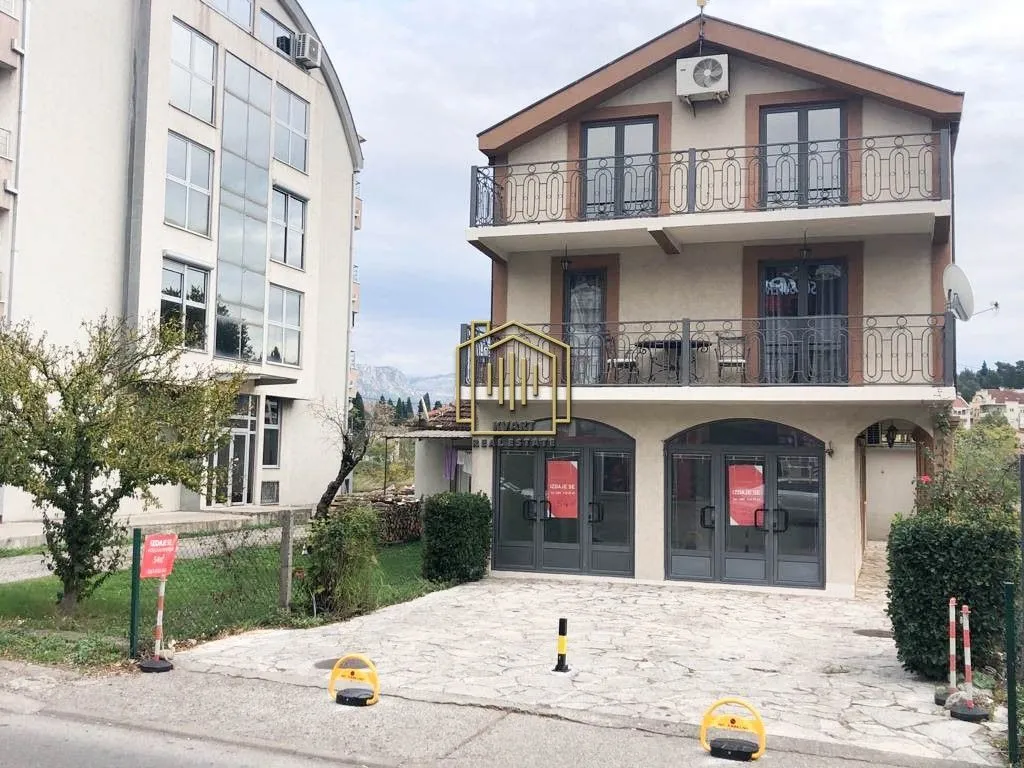 Pogled na spoljašnjost zgrade sa parkingom i terasama.