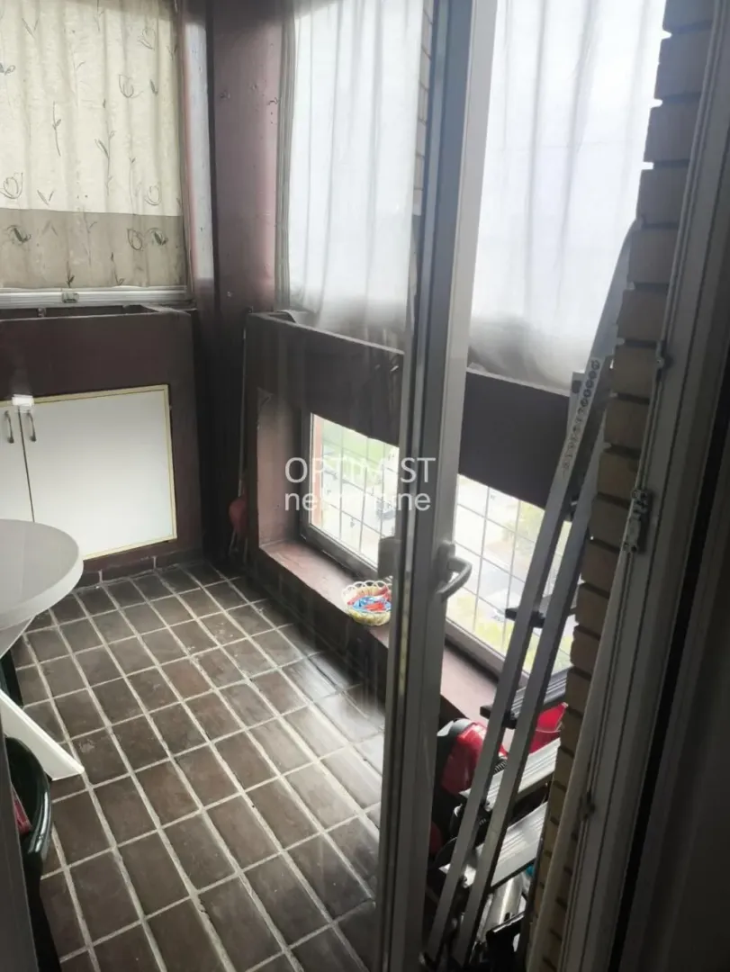 Enclosed balcony with ceramic floor tiles and windows.