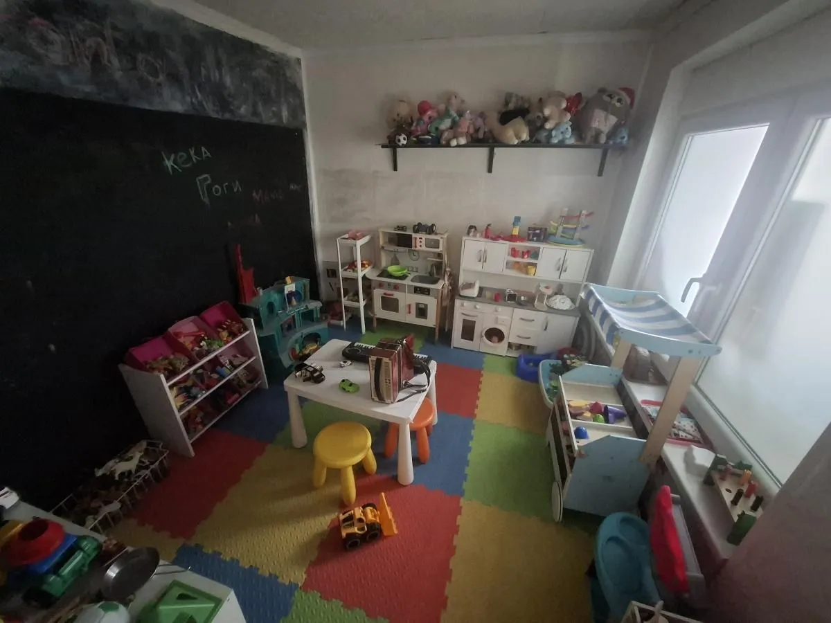 Children's room filled with toys, a play table, and a colorful floor mat.