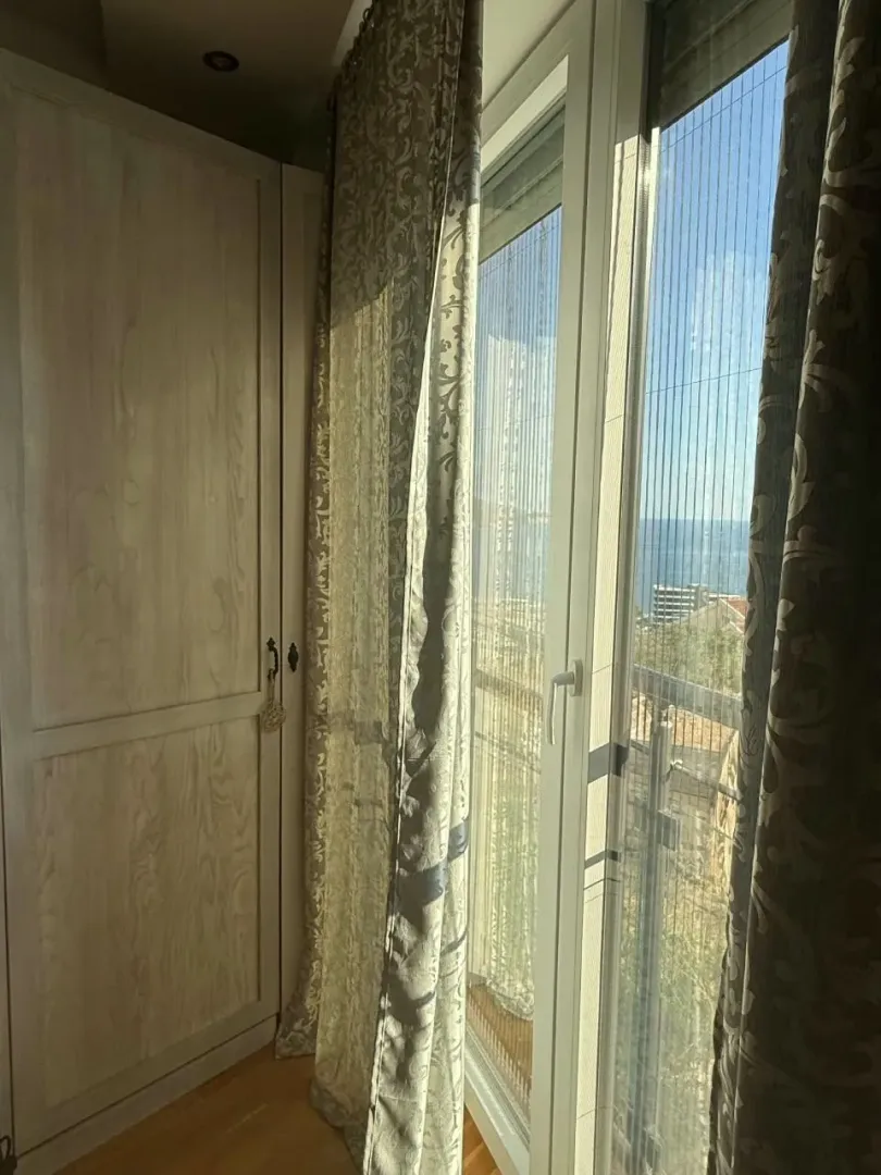 Spavaća soba sa ormarom i prozorom koji gleda na more.