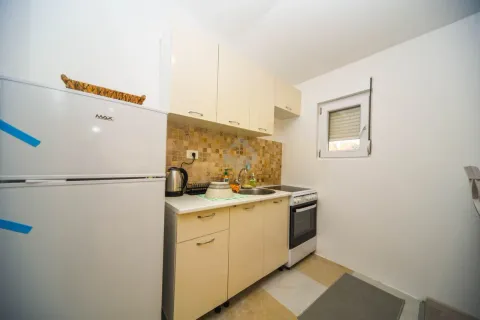 Manja kuhinja sa bijelim elementima, frižiderom i šporetom. - image 5