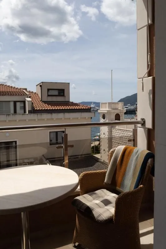 Manji namješteni balkon sa stolom i stolicom, sa pogledom na grad i more.