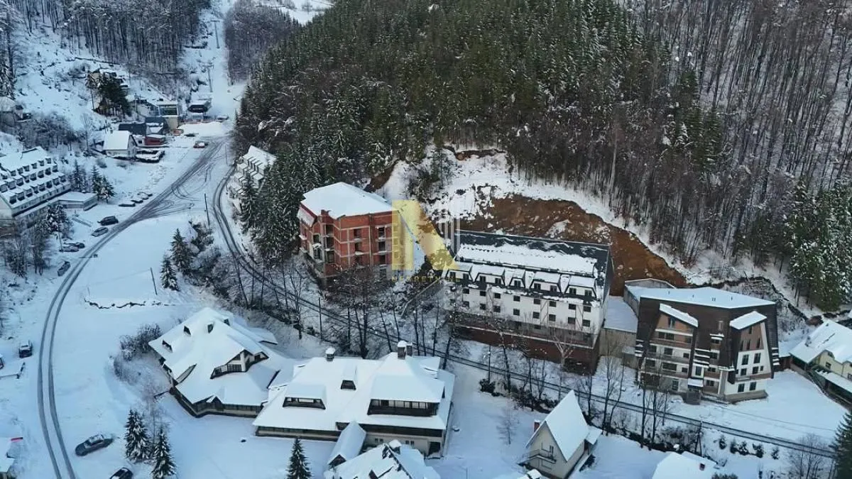 Pogled iz vazduha na planinsko naselje pod snegom.