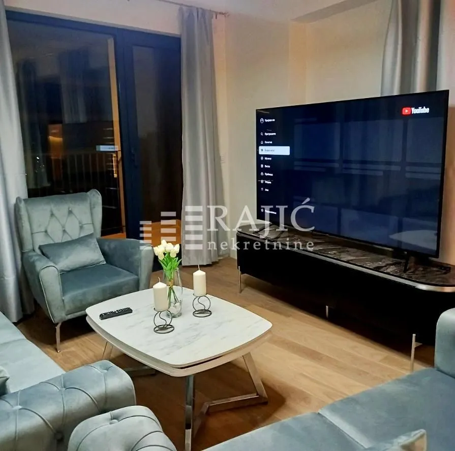 Modern living room with seating set, coffee table, and large TV.