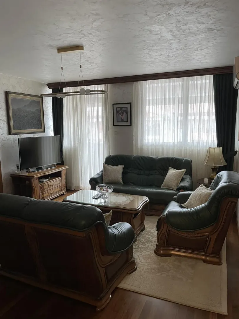 A living room featuring a leather sofa set, wooden furniture, and a TV.
