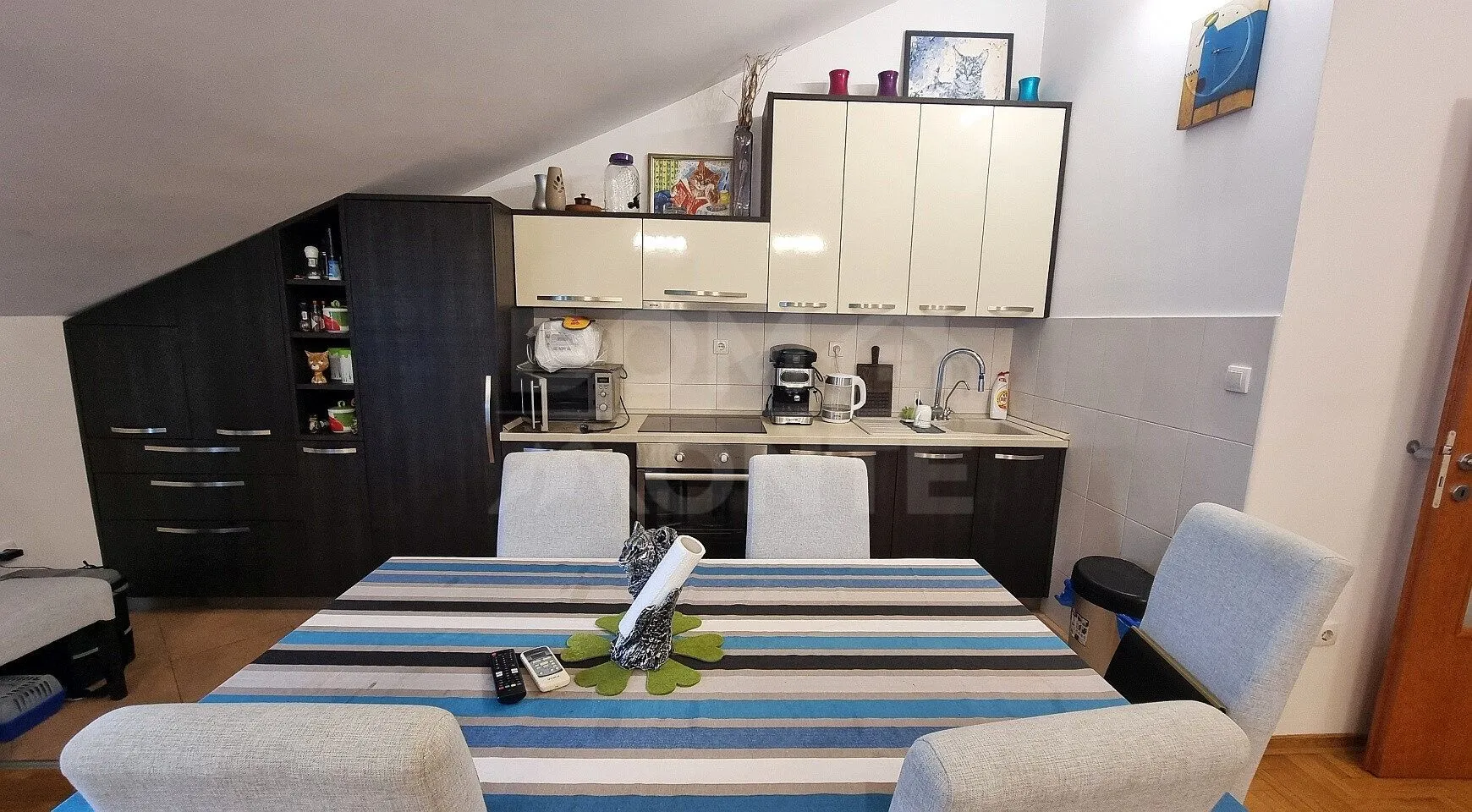 Manja kuhinja sa trpezarijskim stolom i stolicama u potkrovlju.