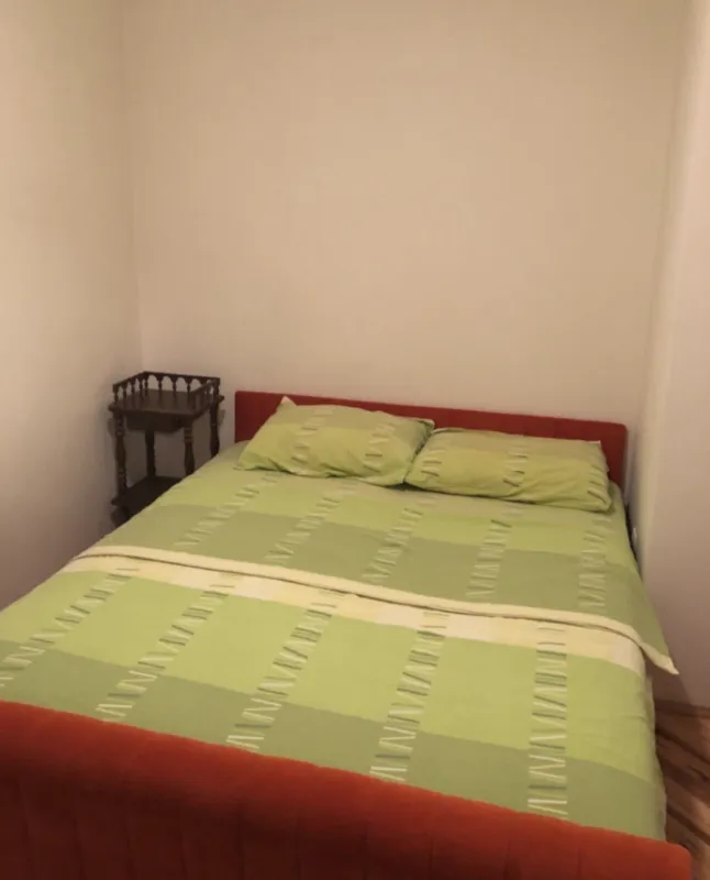 Spavaća soba sa bračnim krevetom i noćnim stočićem.