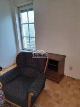 A small armchair and a wooden side table by the window in a room with parquet flooring. - image 2