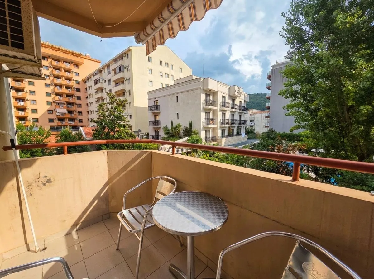 Namješten balkon sa stolom i stolicama i pogledom na gradsko okruženje.