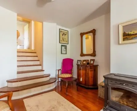 Living room with a fireplace, staircase, and wooden furniture. - image 7
