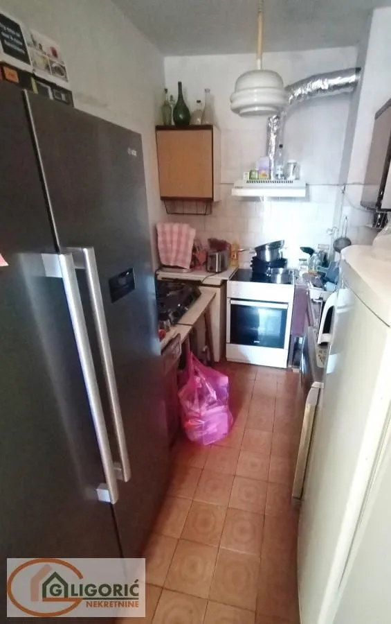 Manja kuhinja sa šporetom, frižiderom i elementima.