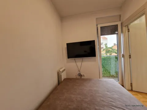 Nameštena spavaća soba sa bračnim krevetom, televizorom na zidu i izlazom na terasu. - image 4