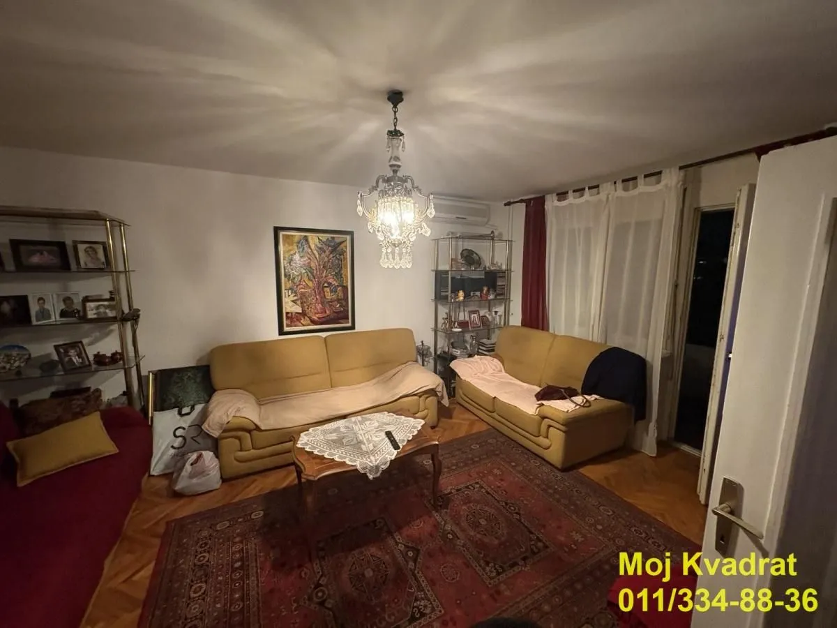 Dnevna soba sa garniturom za sedenje i lusterom.