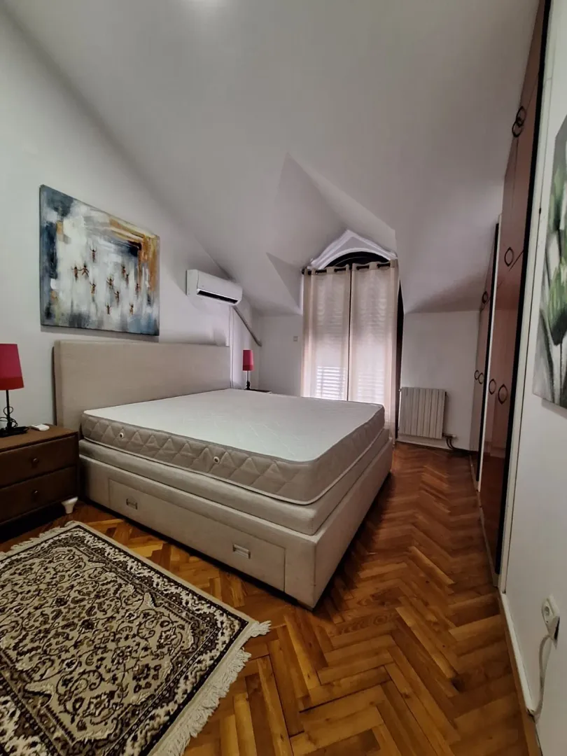 Bedroom with a double bed, wooden parquet flooring, and a wardrobe.