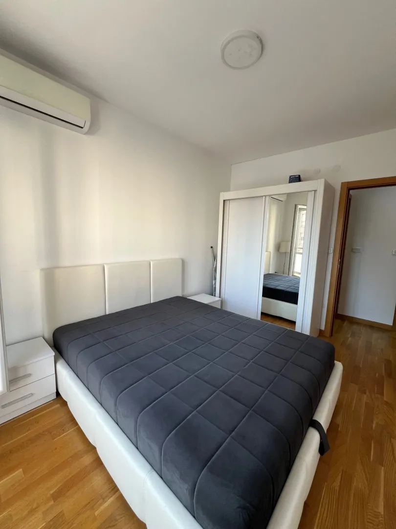 Furnished bedroom with a double bed, white wardrobe, and air conditioning.