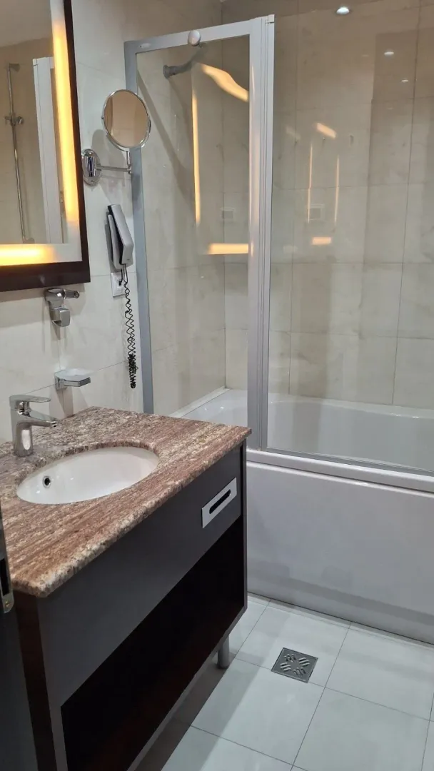 Modern bathroom featuring a vanity sink and a bathtub with a glass screen.