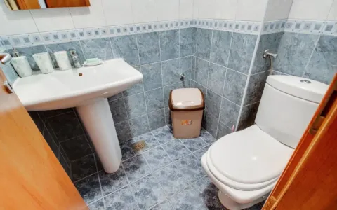 Small tiled bathroom with a washbasin and toilet. - image 12