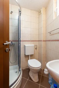 Bathroom equipped with a shower cabin, toilet, and sink. - image 18