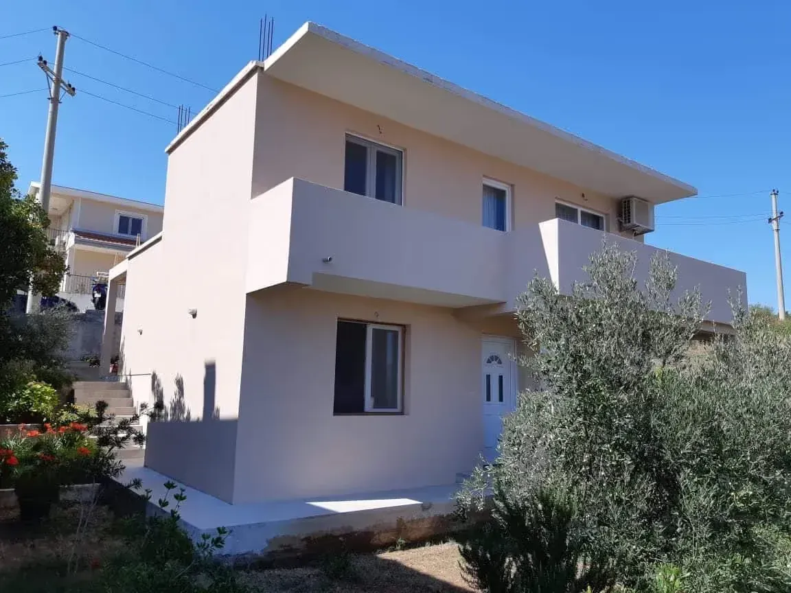 Pogled na spoljašnjost kuće sa balkonom i dvorištem.