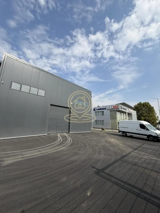 View of the exterior of an industrial building with a paved yard and a van.