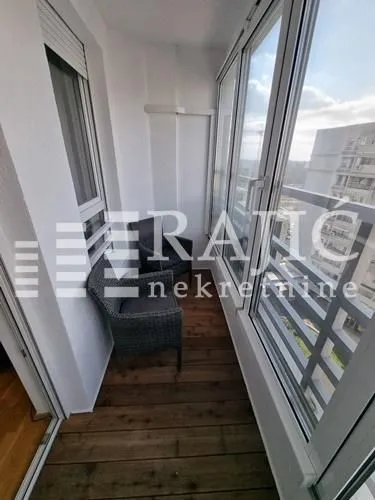 Enclosed balcony with wooden flooring and two armchairs.