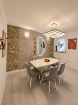 Trpezarija sa modernim stolom, stolicama i dekorativnim kamenim zidom. - image 4