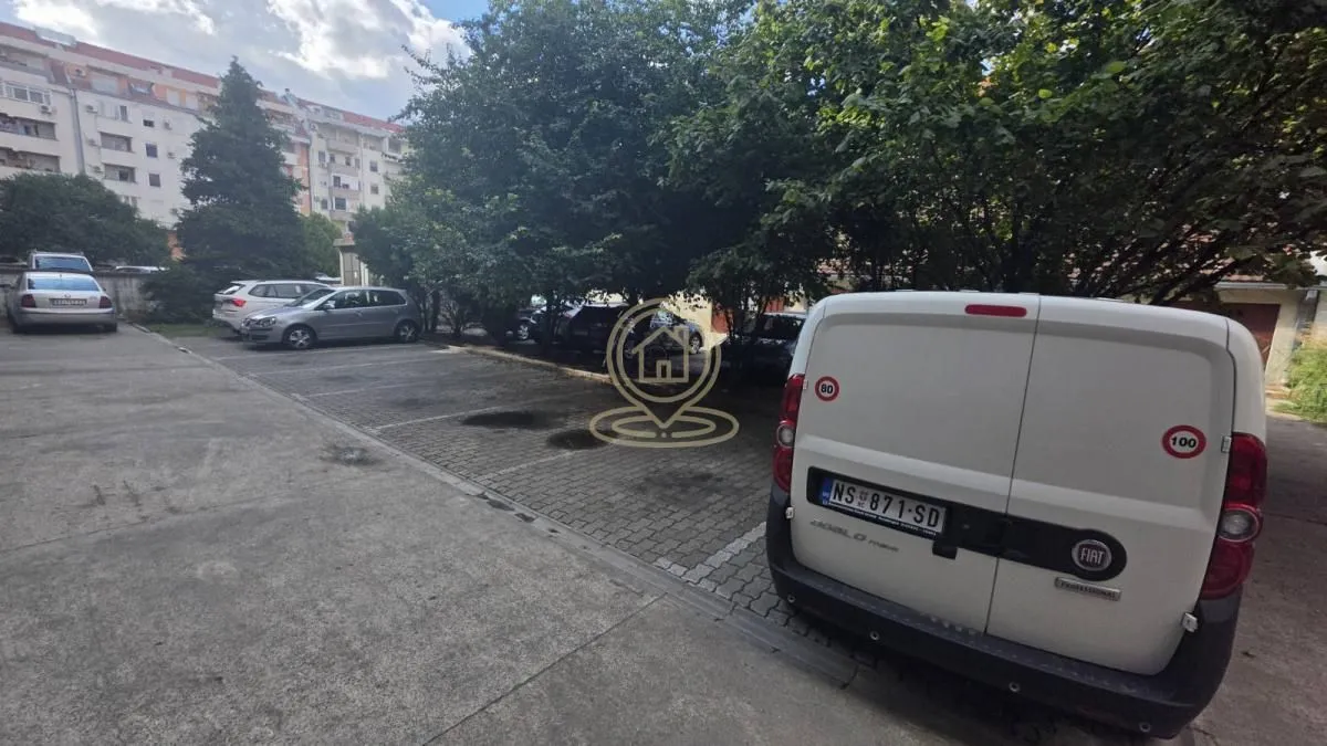 Parking prostor ispred zgrade sa parkiranim automobilima.