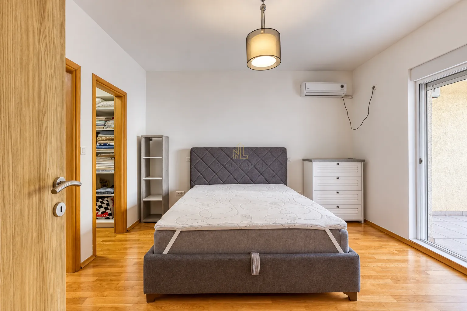 Furnished bedroom with a double bed, air conditioning, and balcony access.
