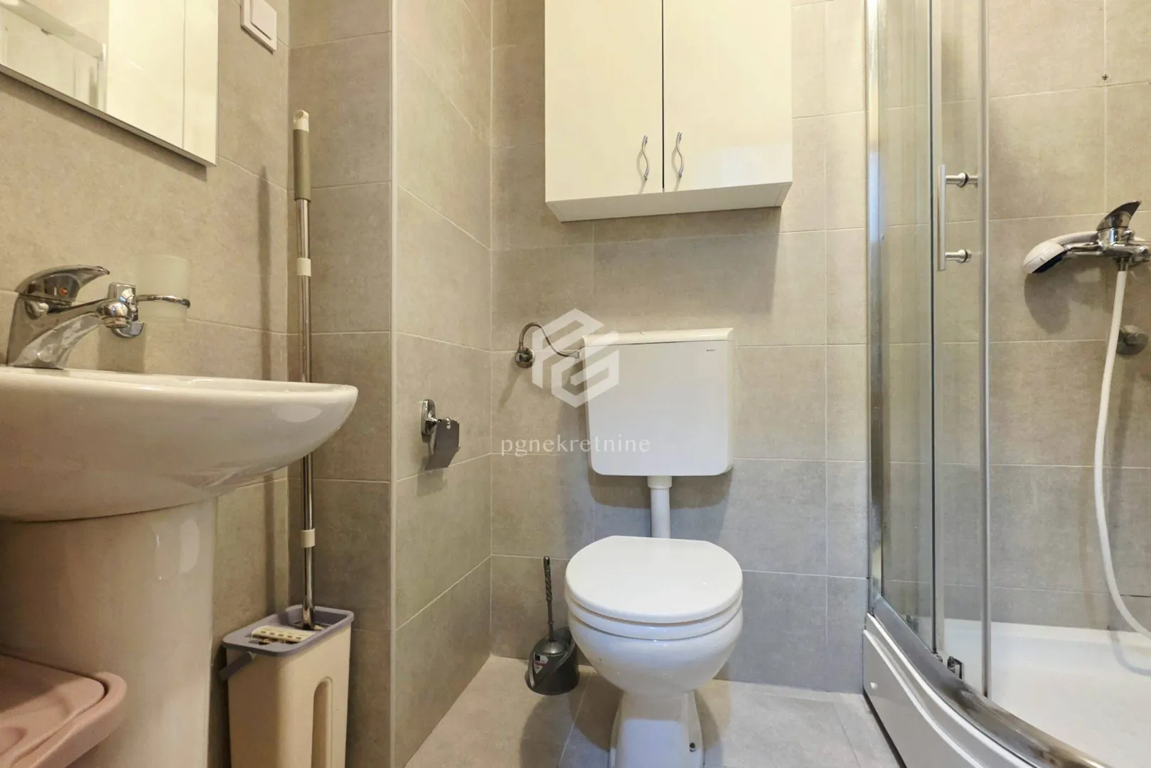 Manje kupatilo sa tuš kabinom, umivaonikom i wc šoljom.
