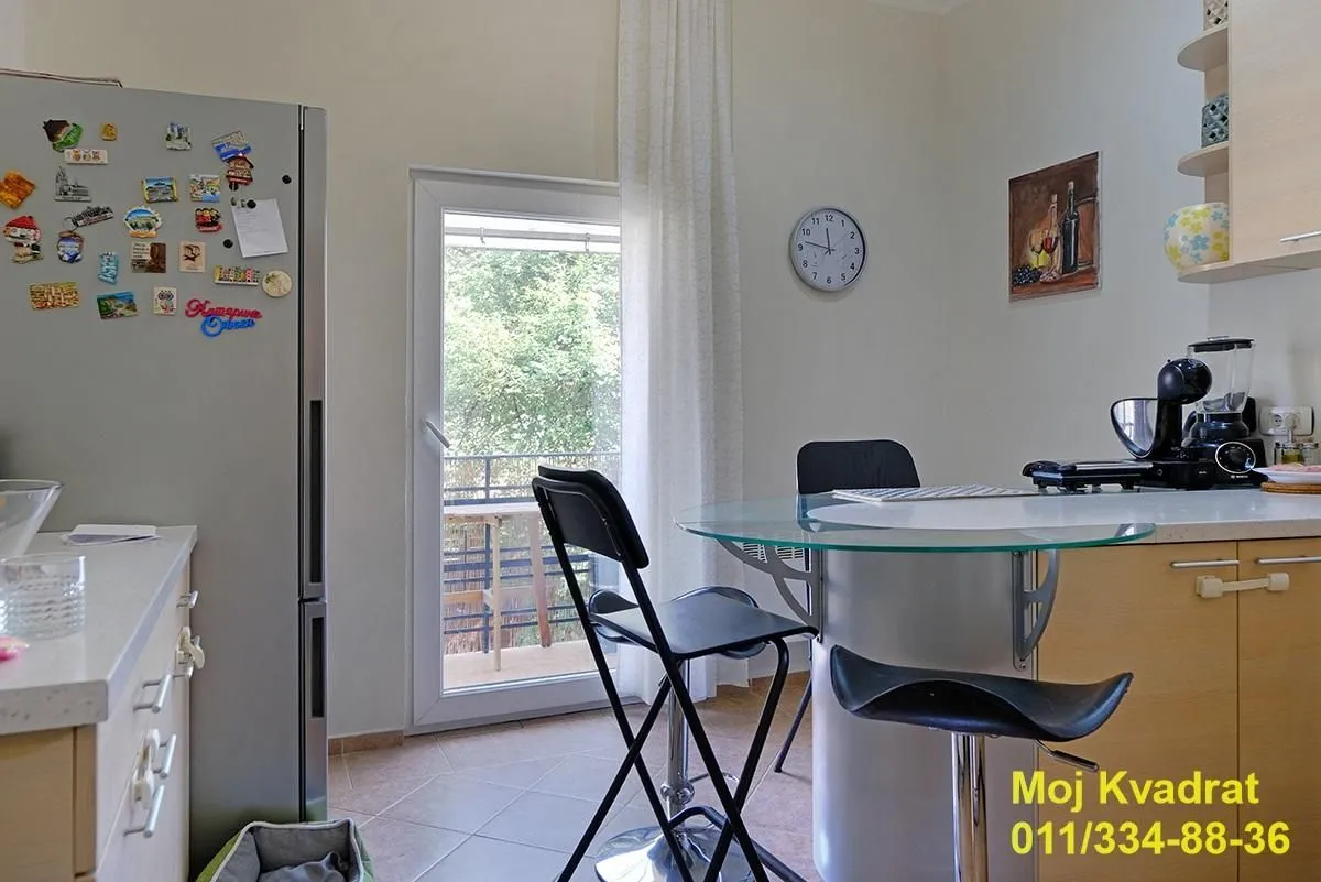 Manja kuhinja sa trpezarijskim stolom i izlazom na terasu.