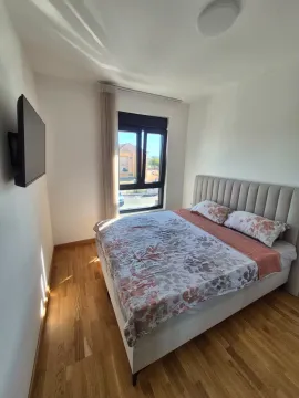 Spavaća soba sa bračnim krevetom, drvenim podom i televizorom na zidu. - image 5