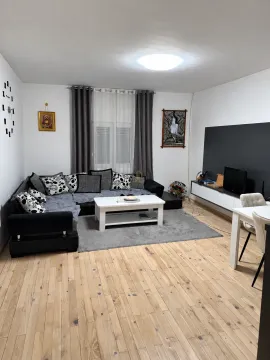 Living room with a sectional sofa, coffee table, and TV unit. - image 3