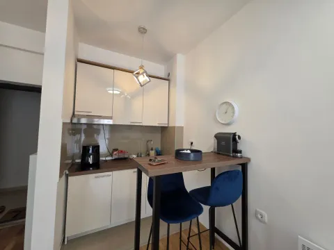 Mala kuhinja sa bijelim elementima i šankom za ručavanje sa plavim stolicama. - image 8
