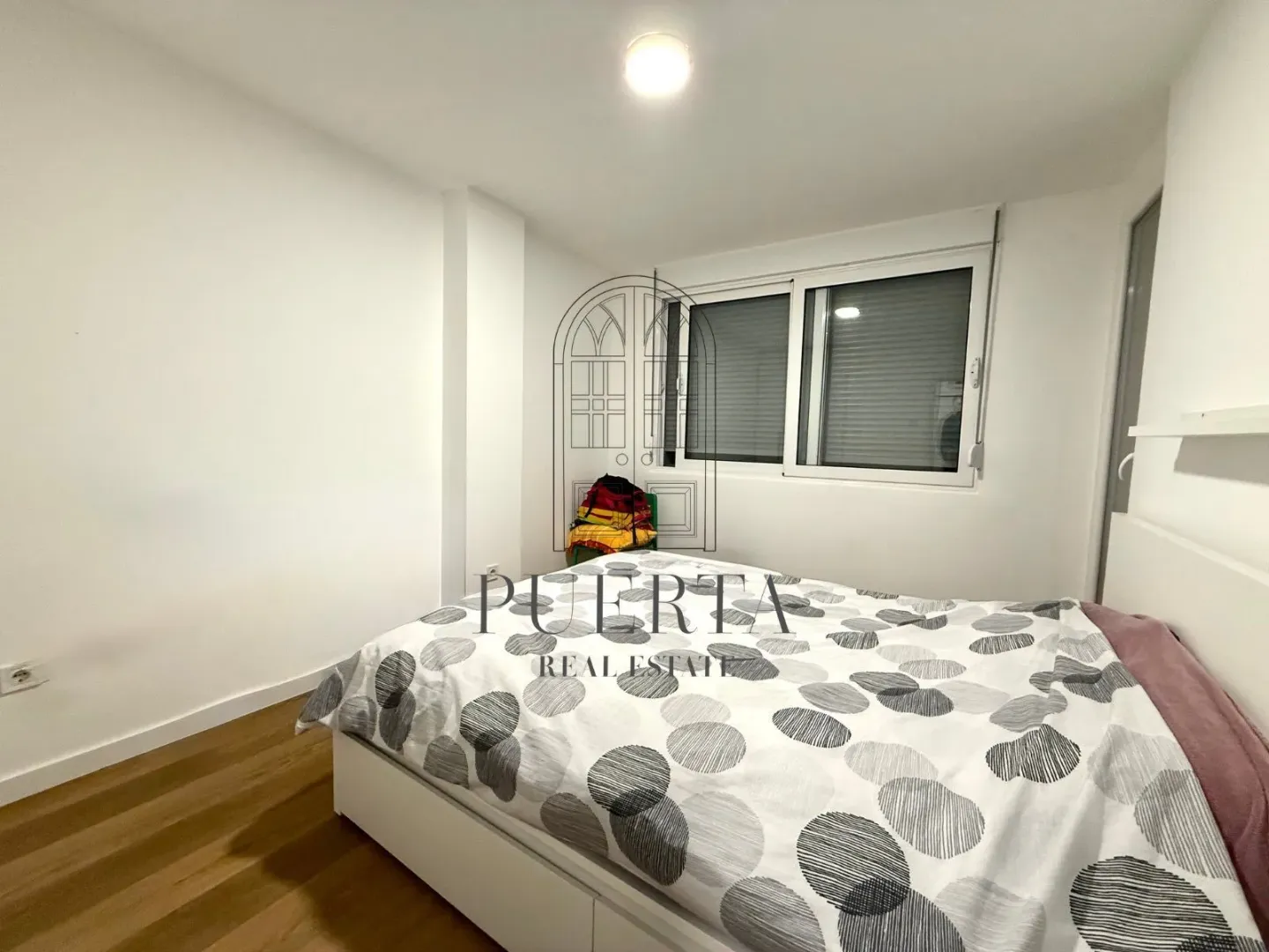 Bright bedroom with a double bed and wooden flooring.