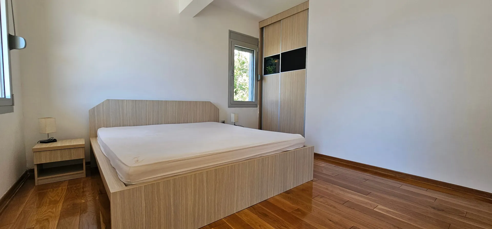 Bright bedroom with a double bed, wooden floor and built-in wardrobe.