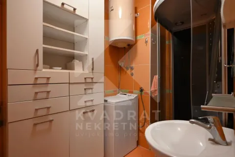 Bathroom with a shower cabin, washbasin, cabinet, and washing machine. - image 19