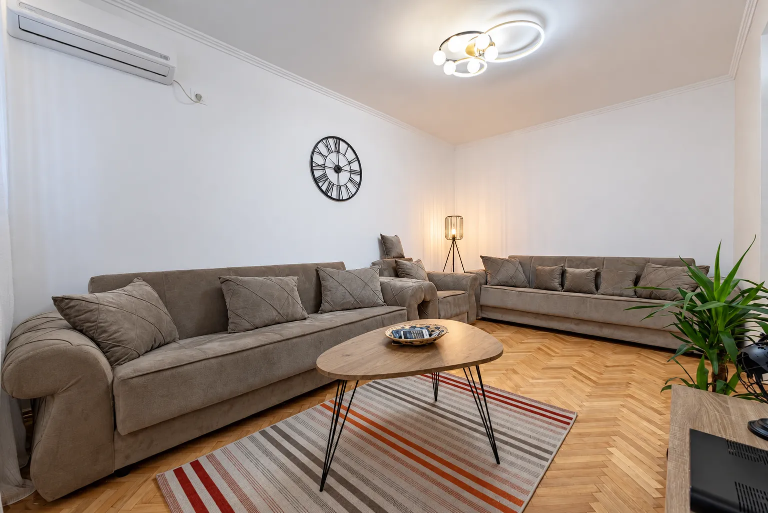 Living room with a sofa set, coffee table, and parquet flooring.